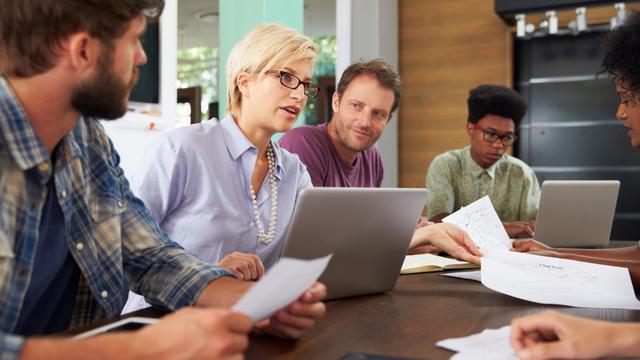 Group of people working together at a desk in an office