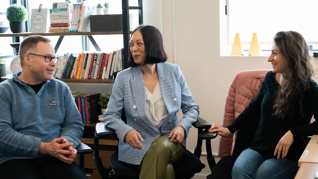 hiring an external IT company - Picture of three coworkers sitting together chatting and smiling