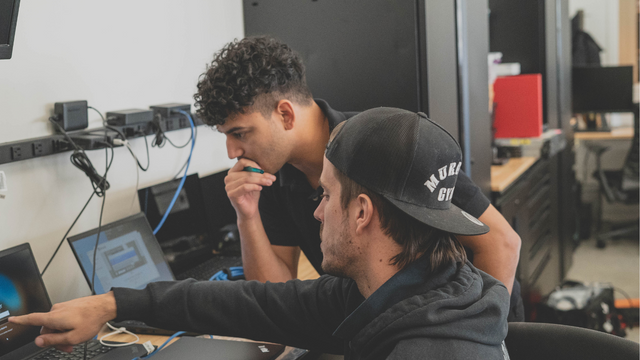 Picture of two coworkers working closely together on a laptop